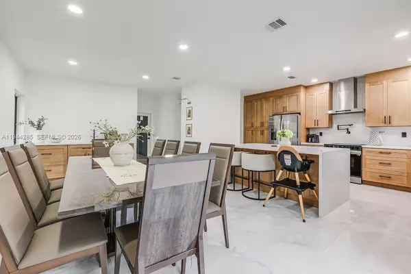 a dining room with kitchen island furniture a sink a kitchen island and stainless steel appliances