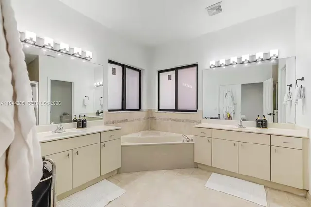 a bathroom with a double vanity sink mirror and bathtub