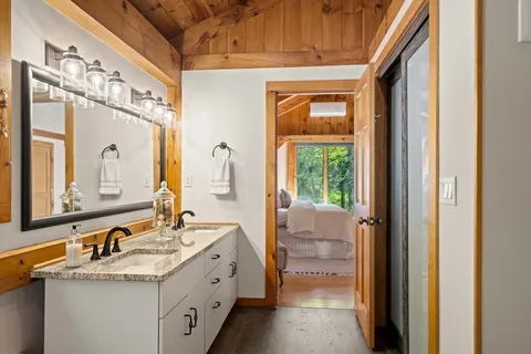 a bathroom with a double vanity sink and mirror with bathtub