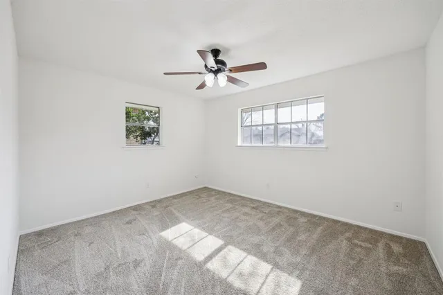 an empty room with windows and fan