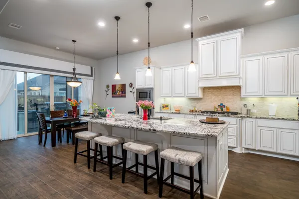 a kitchen with kitchen island granite countertop a sink a stove a dining table and chairs