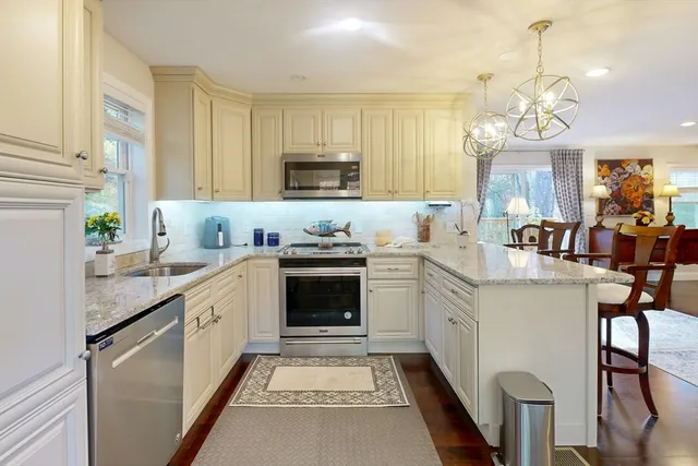 a kitchen with kitchen island granite countertop a sink a counter space appliances and cabinets