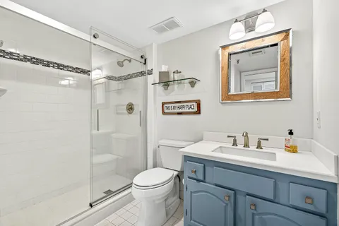 a bathroom with a shower sink vanity mirror and toilet