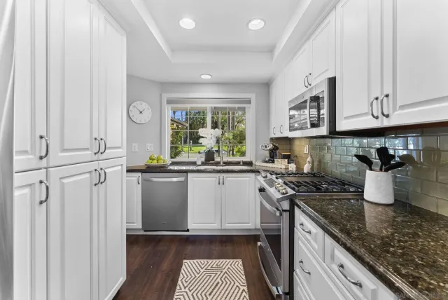 a kitchen with stainless steel appliances granite countertop a stove a sink and a white cabinets