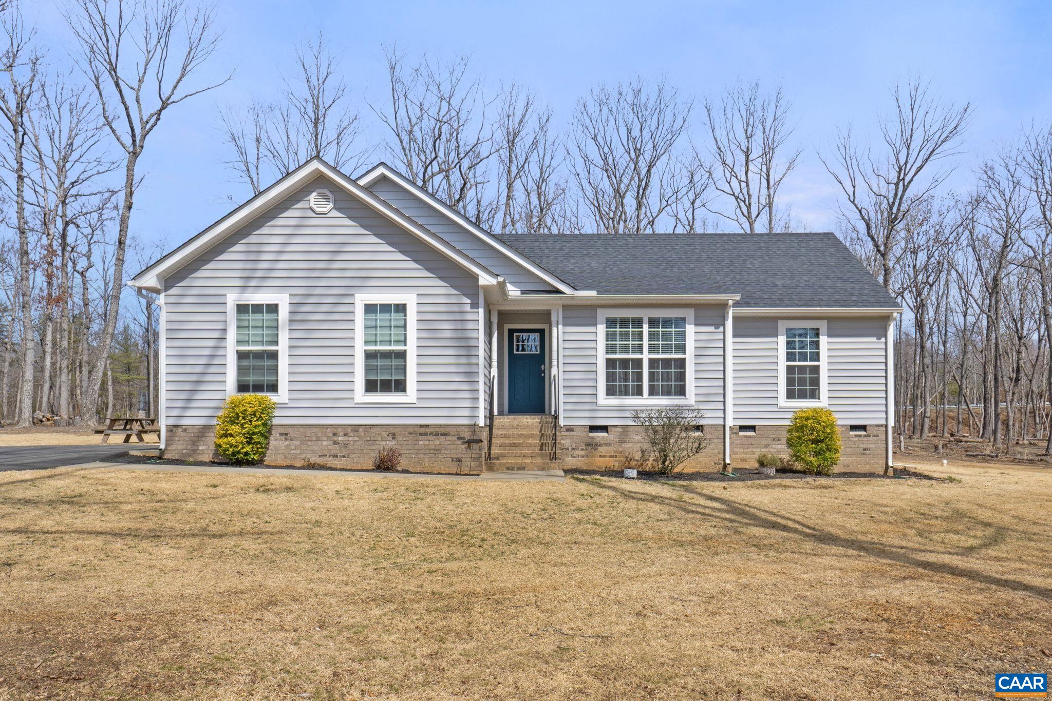 a front view of a house with large trees and covered with snow