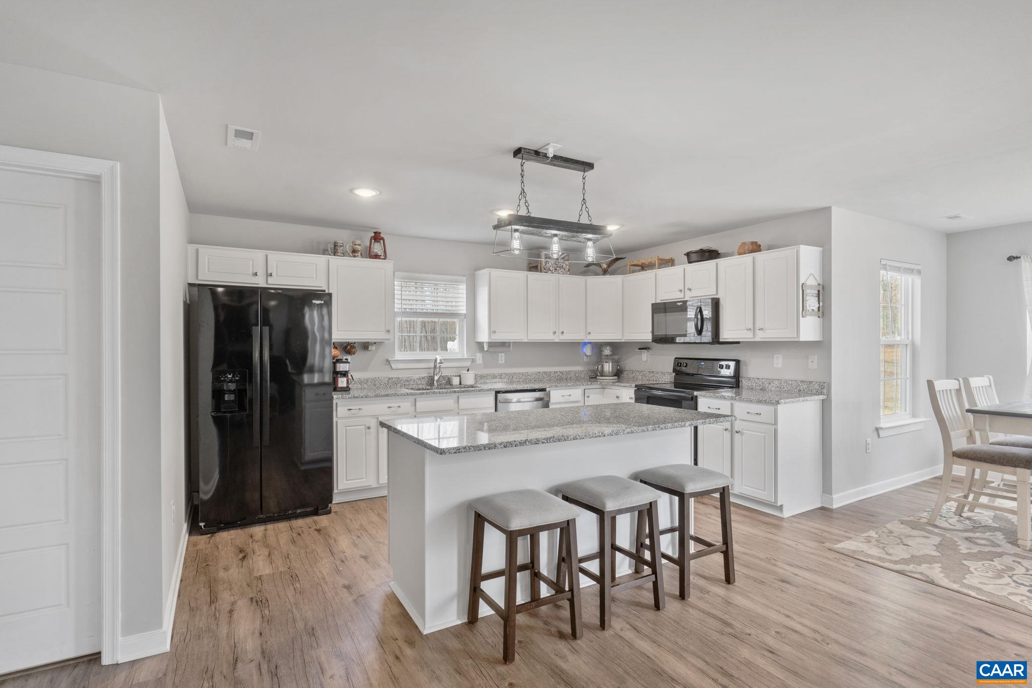 1075 Pine Crest Drive Troy, VA 22974 - Photo 11 of 25 a kitchen with stainless steel appliances a dining table chairs refrigerator and wooden cabinets
