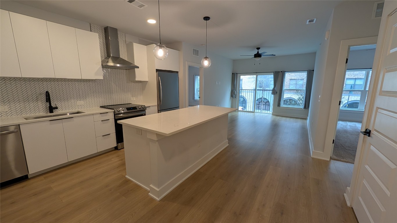 2500 Longview Street, Unit 218 Austin, TX 78705 - Photo 5 of 19 Kitchen featuring modern cabinets, white cabinets, appliances with stainless steel finishes, wall chimney range hood, and recessed lighting