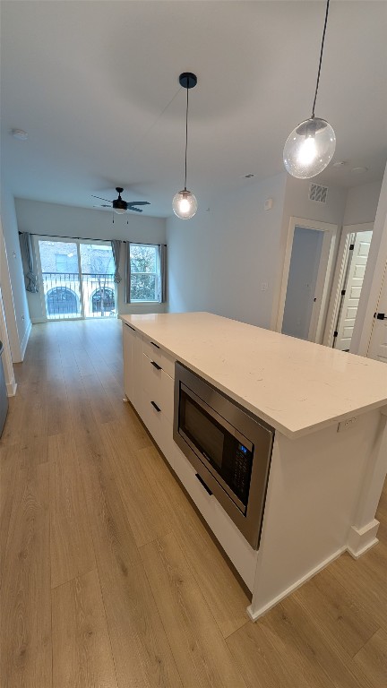 2500 Longview Street, Unit 218 Austin, TX 78705 - Photo 8 of 19 Kitchen with hanging light fixtures, white cabinets, a center island, and light wood-style floors