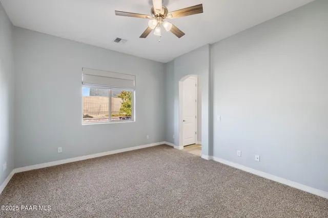 an empty room with windows and fan