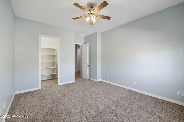 an empty room with closet and a ceiling fan
