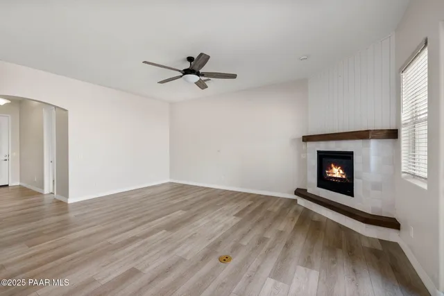 a view of an empty room with wooden floor fireplace and a window