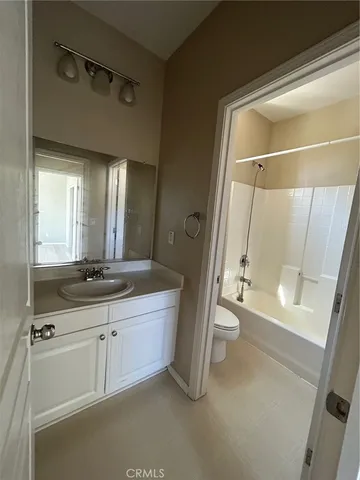 a bathroom with a double vanity sink toilet mirror and next to a window