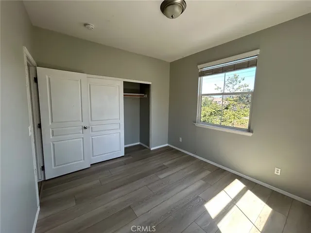 an empty room with wooden floor cabinet and windows