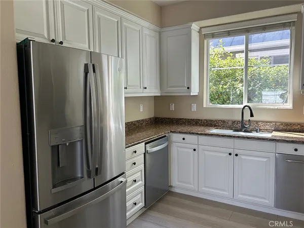 a kitchen with granite countertop white cabinets white stainless steel appliances and a sink