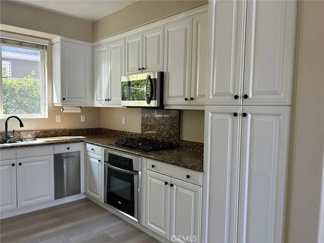 a kitchen with stainless steel appliances granite countertop a sink a stove and a microwave