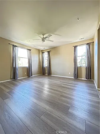 a view of an empty room with wooden floor and window