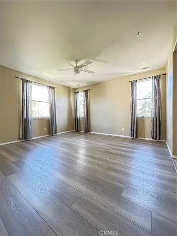 a view of an empty room with wooden floor and window