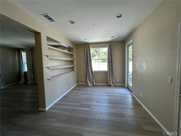 a view of a hallway with wooden floor stairs and a living room