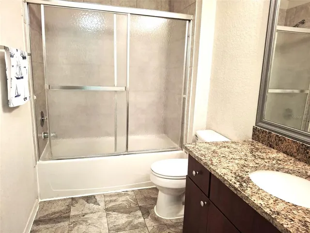 a bathroom with a granite countertop shower a toilet and a sink