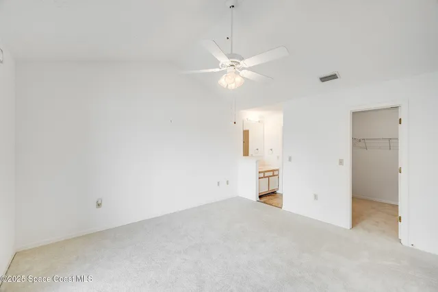 an empty room with closet and a ceiling fan