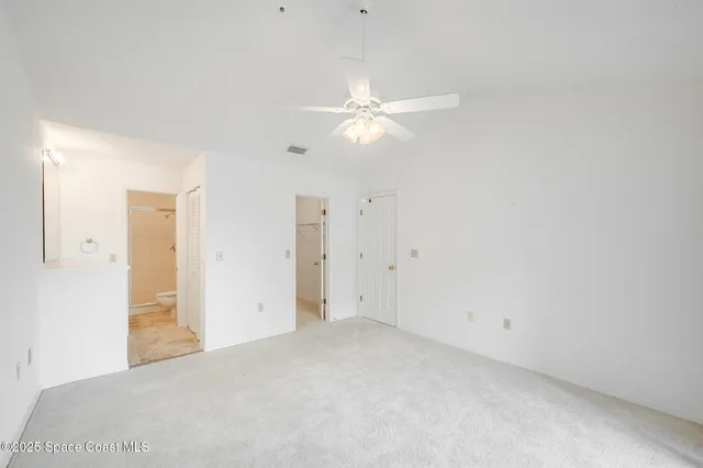 an empty room with closet and a ceiling fan