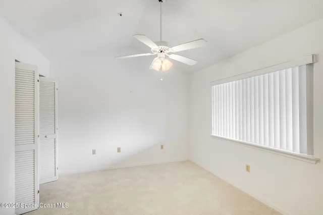 an empty room with a window and a fan