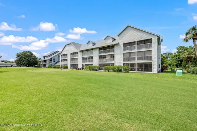 a view of a house with a big yard and large trees