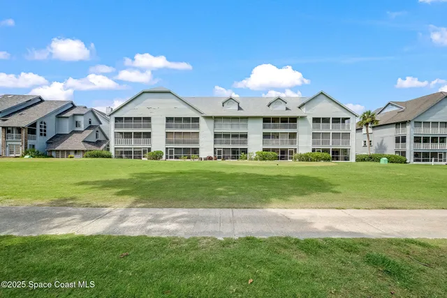 a view of a house with a big yard and large trees