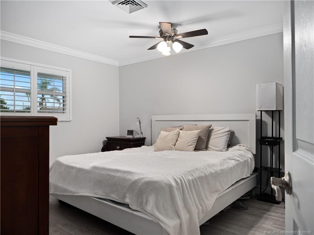 1544 Northwest Spruce Ridge Drive Stuart, FL 34994 - Photo 14 of 23 a bedroom with a bed and a chandelier