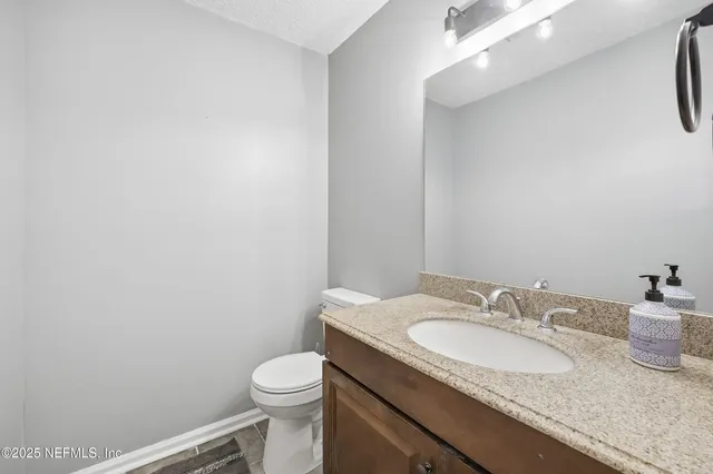 a bathroom with a granite countertop sink and a toilet