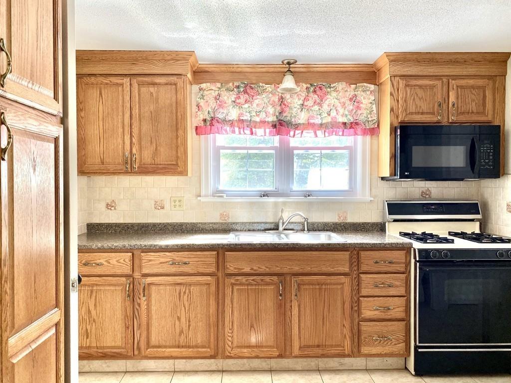 271 Gillette Avenue Springfield, MA 01118 - Photo 4 of 33 a kitchen with granite countertop a stove a sink and a microwave