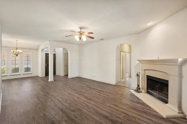 an empty room with wooden floor a fireplace and windows