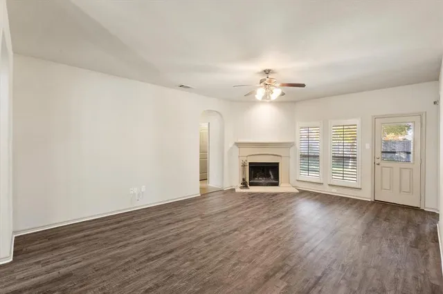 a view of an empty room with a window and kitchen view