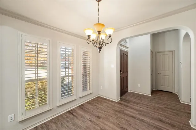 a view of a room with wooden floor chandelier and windows