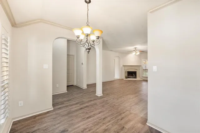 a view of an empty room with wooden floor fireplace and a window