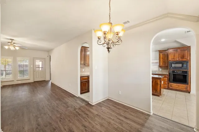 an empty room with wooden floor and ceiling fan