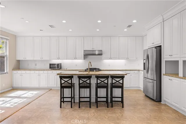 a kitchen with a refrigerator a stove a sink and white cabinets with wooden floor