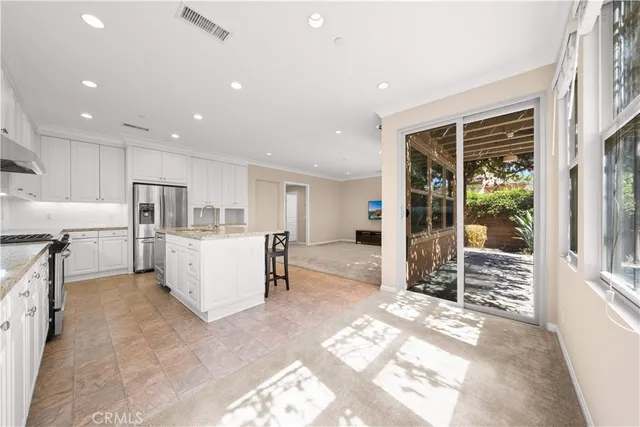 a large white kitchen with stainless steel appliances kitchen island granite countertop a refrigerator and a sink