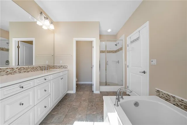 a bathroom with a granite countertop double vanity sink a mirror and a bathtub