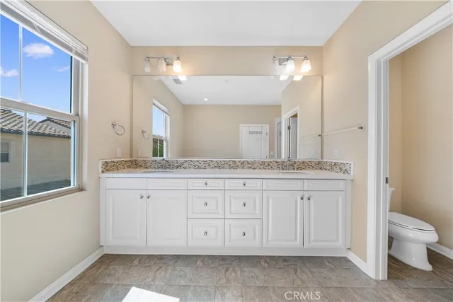a bathroom with a granite countertop double vanity sink and a mirror
