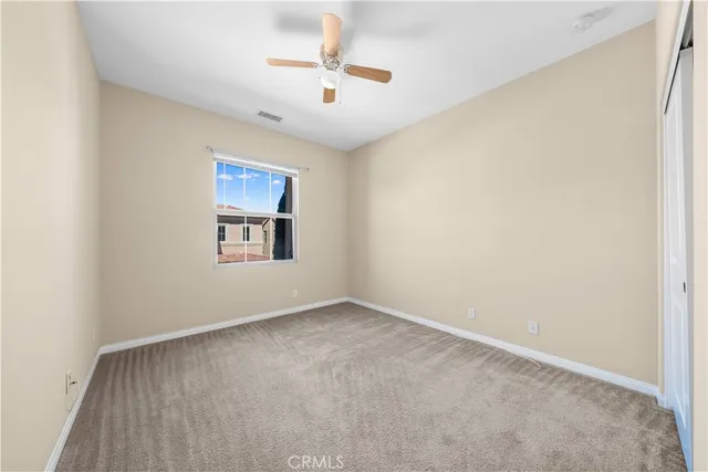 an empty room with windows and ceiling fan