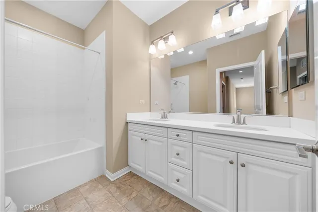a bathroom with a bathtub a double vanity sink and a mirror