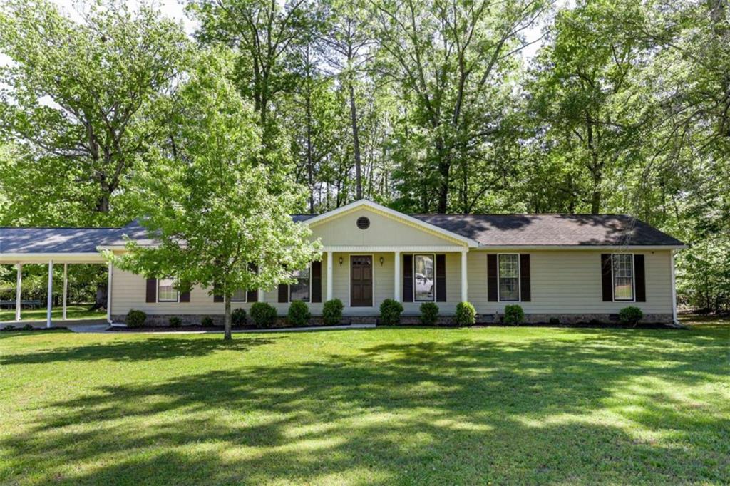 a front view of a house with a garden and trees