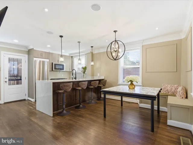 a room with stainless steel appliances kitchen island a table chairs in it and wooden floors