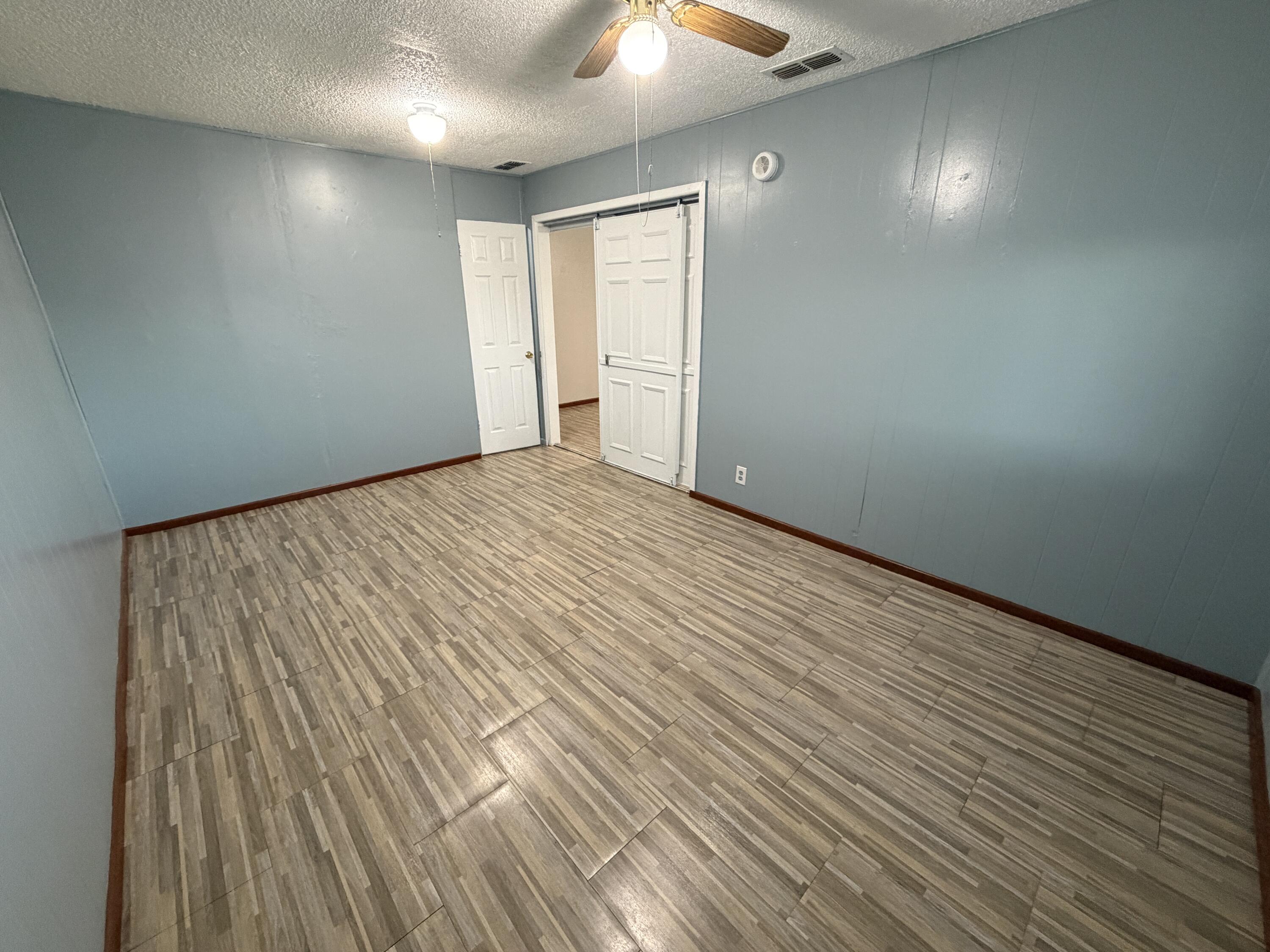 5720 46th Street Lubbock, TX 79414 - Photo 11 of 23 an empty room with wooden floor and windows
