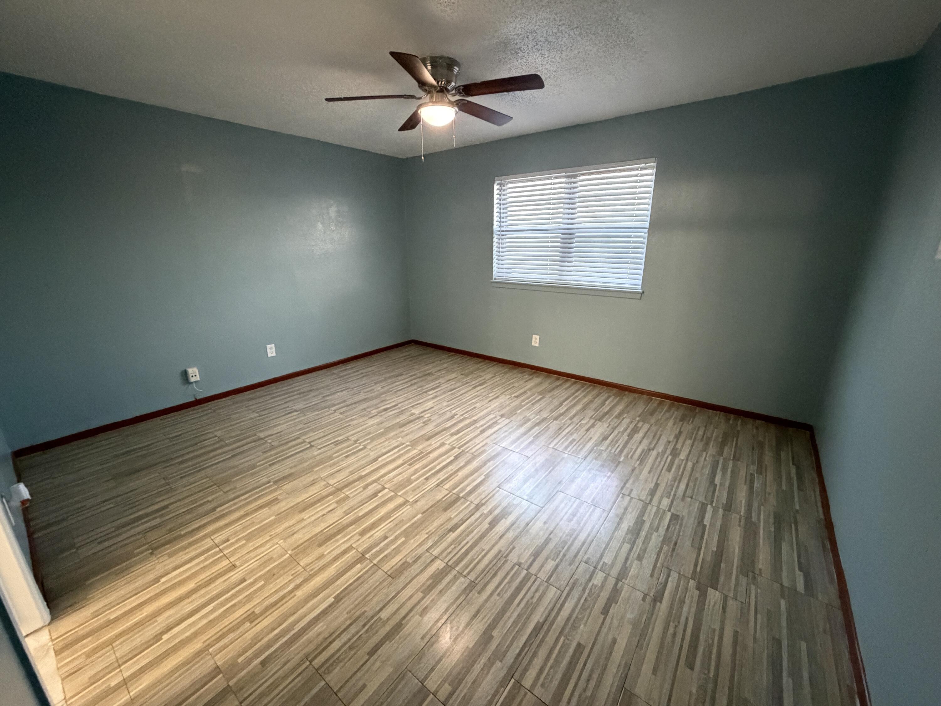 5720 46th Street Lubbock, TX 79414 - Photo 12 of 23 an empty room with wooden floor ceiling fan and windows