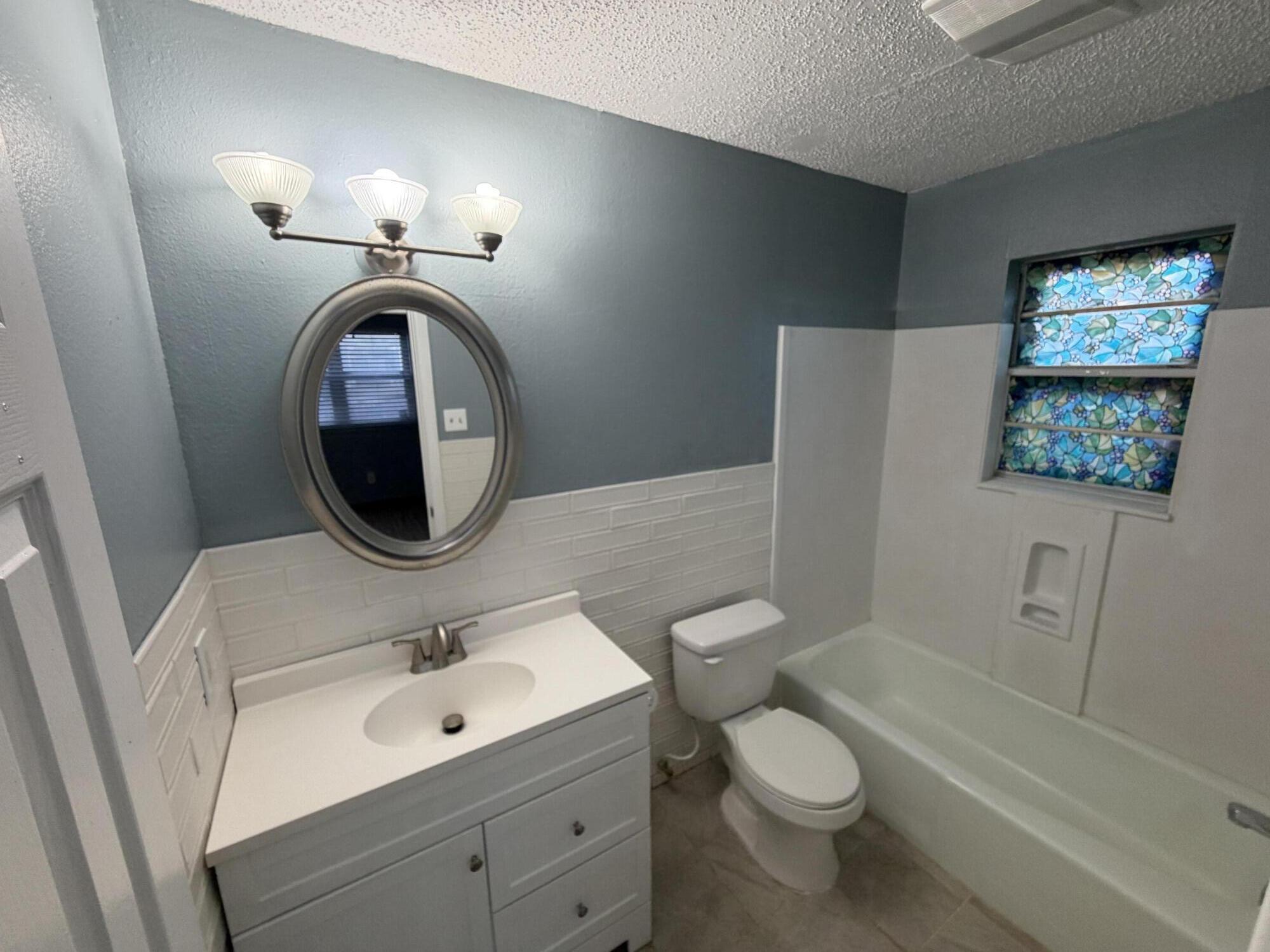 5720 46th Street Lubbock, TX 79414 - Photo 15 of 23 a bathroom with a toilet a sink a tub and mirror