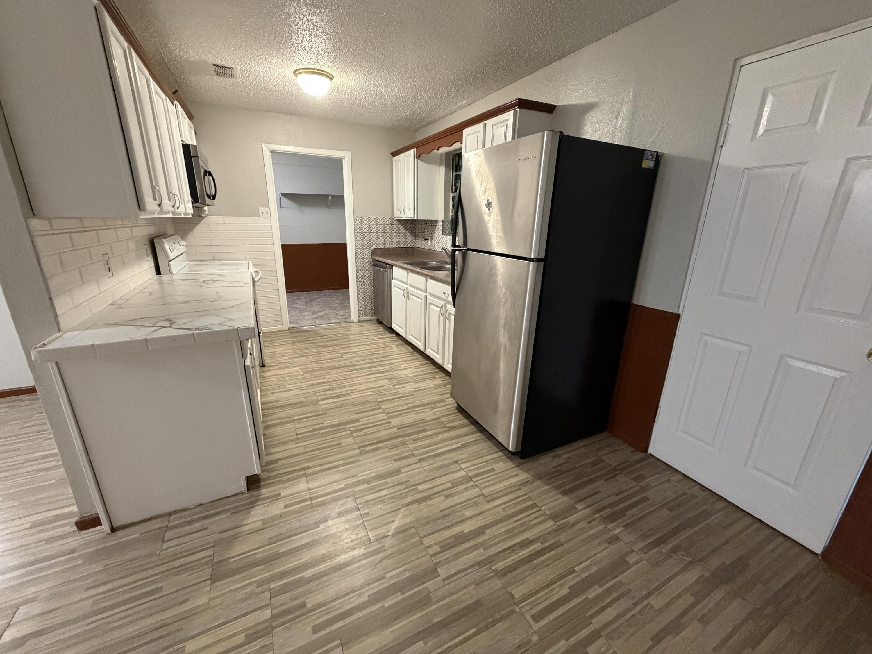 5720 46th Street Lubbock, TX 79414 - Photo 5 of 23 a kitchen with a refrigerator sink and wooden floor
