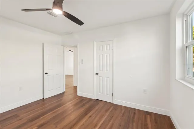an empty room with wooden floor cabinet and windows