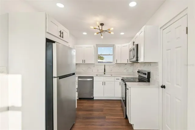 a kitchen with a refrigerator a sink and dishwasher with white cabinets